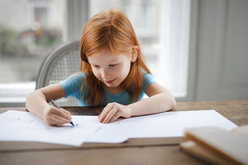 Описание картинки на немецком: девочка рисует за столом